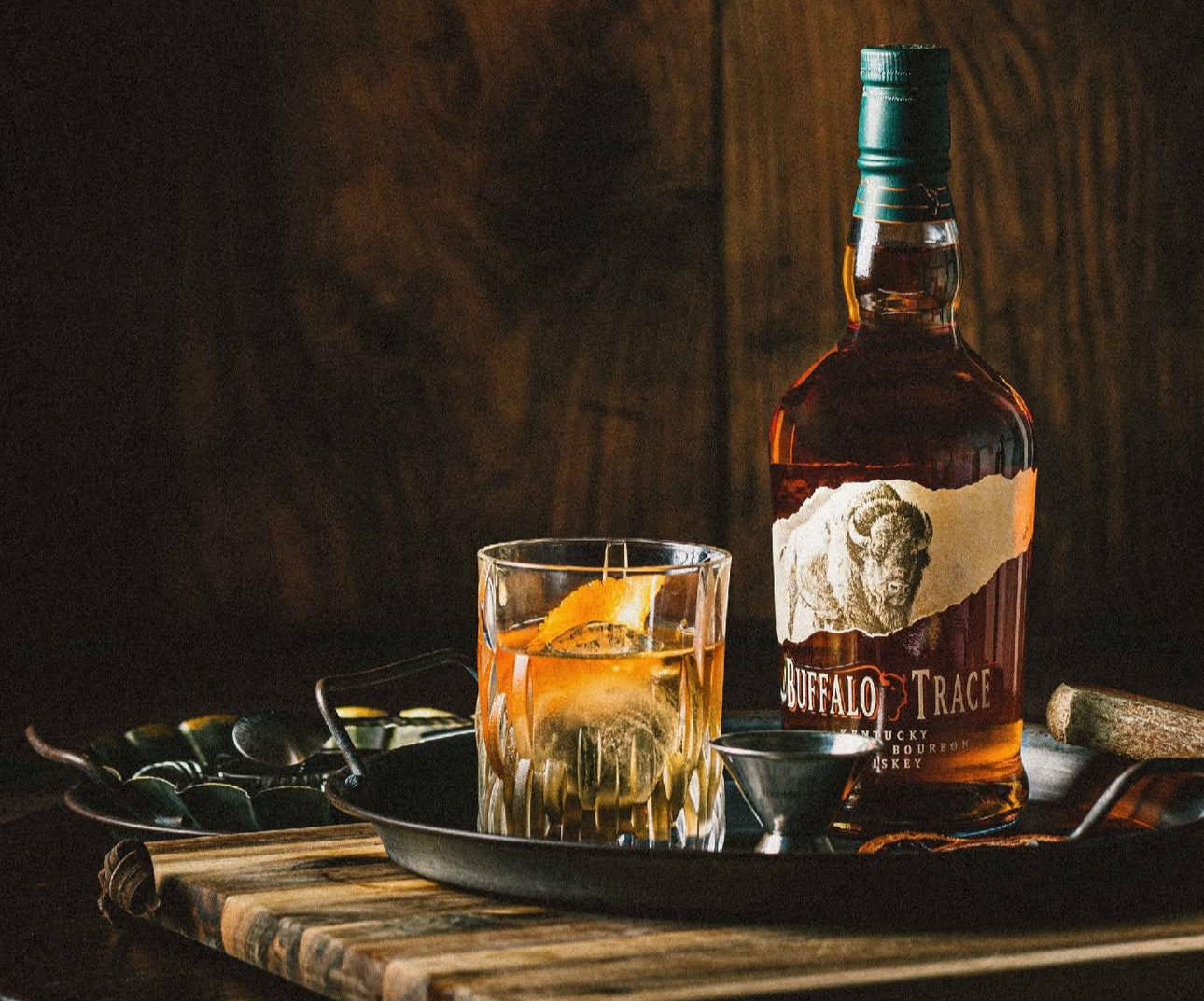 Buffalo Trace Bourbon bottle with an old-fashioned cocktail on a rustic tray.